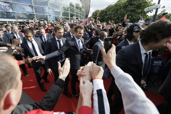 Paris Saint-Germain's British midfielder David Beckham (C) shakes hands with supporters as he arrives with the squad to parade in a double decker, on May 13, 2013 in Paris