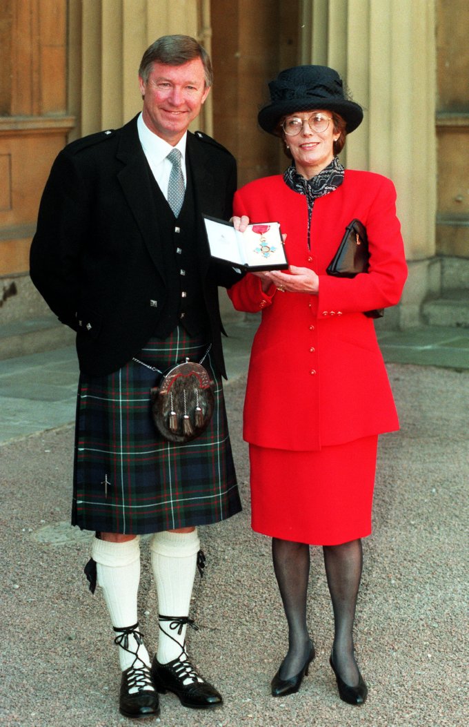 Dressed to the hilt, Ferguson and wife Cathy pose outside Buckingham Palace after receiving his CBE from the Prince of Wales, March 1995